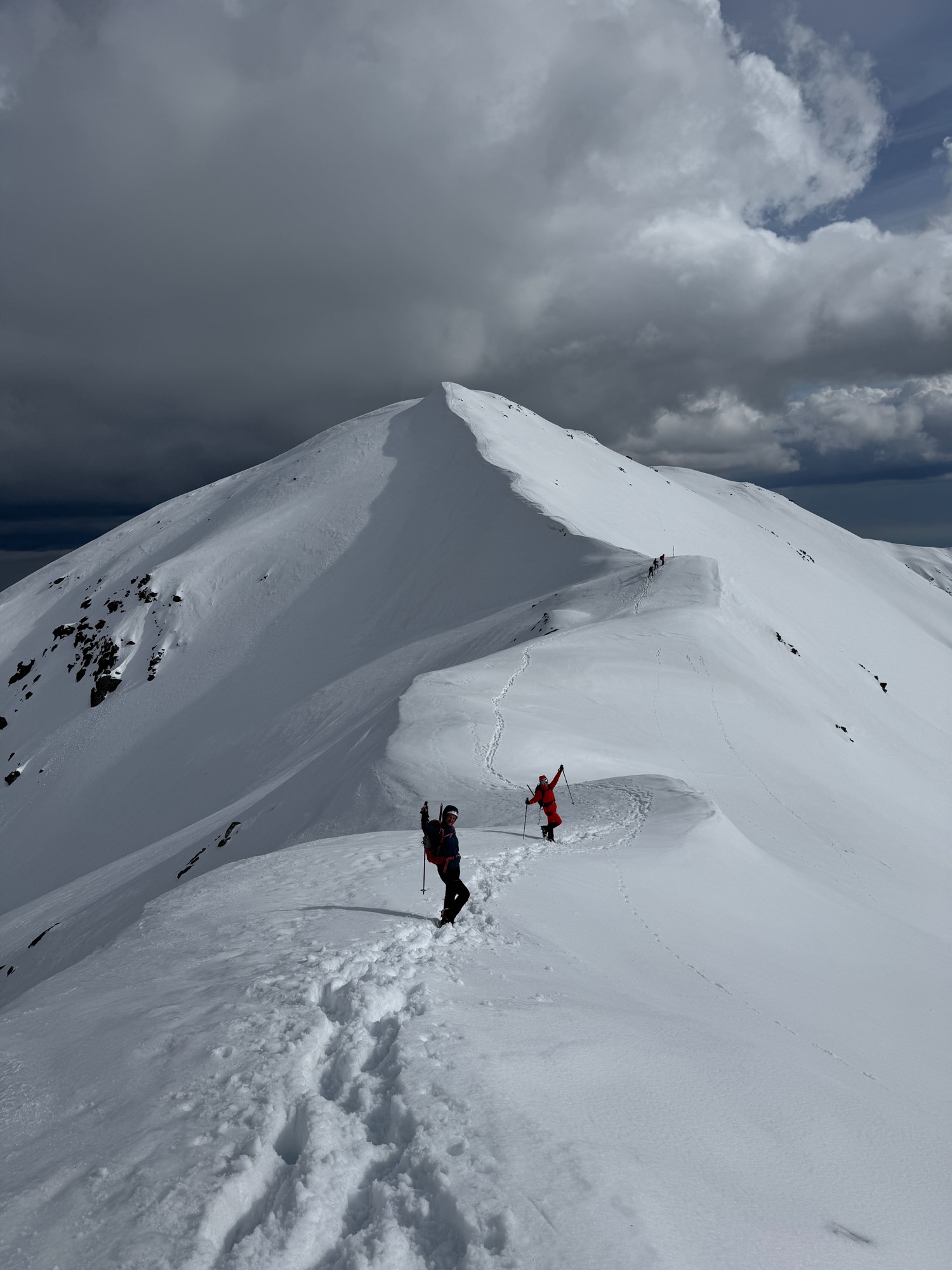 Two hikers crossing a snow-covered mountain ridge